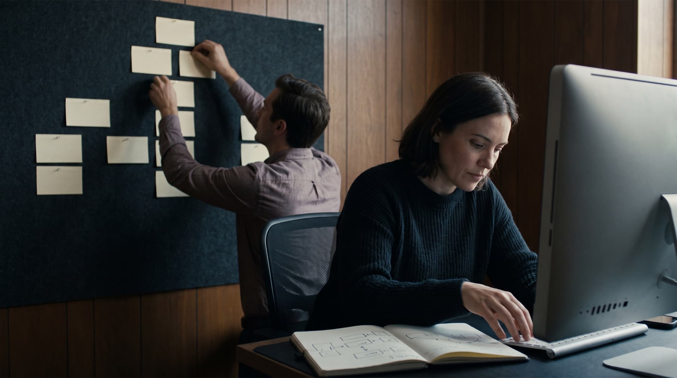 Two strategists mapping a content structure with hand-drawn diagrams and index cards pinned to a board.